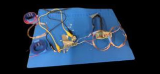 The scaled Electric Road test model: hand-wound copper coils on a blue mat, a green receiver board and a breadboard