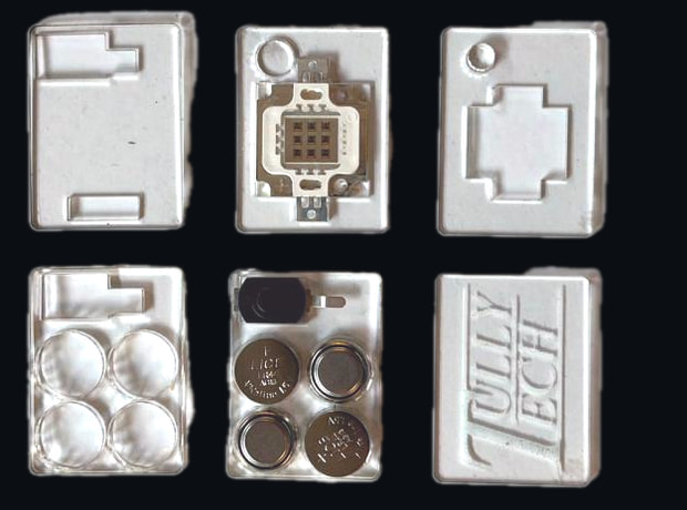 Six clear laser-cut acrylic plates for the AntiCam V2 pin laid flat: the LED plate with its module, a plate with four coin cells and a slide switch, spacer plates and the engraved lid