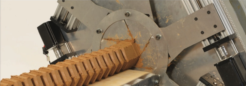 A ribbed hexagonal clay pipe comes out of the shape-shifting die onto the conveyor of the extruder