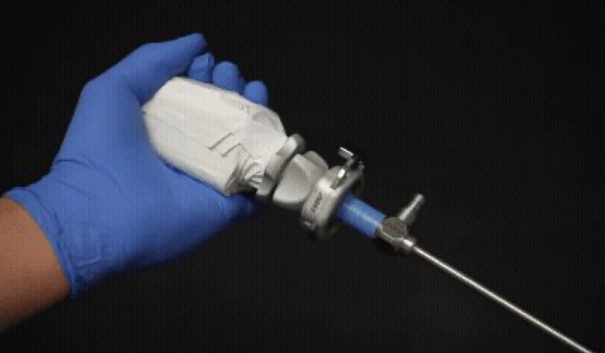 A gloved hand grips a laparoscope's camera head while the scope is turned by its light post: the two-handed rotation