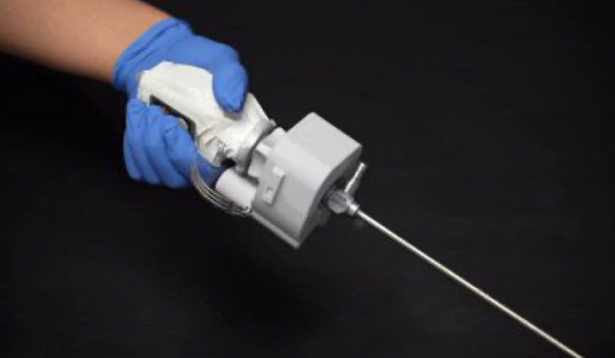 A gloved hand holds a laparoscope fitted with the white LapRotator attachment, turning the scope with the same hand